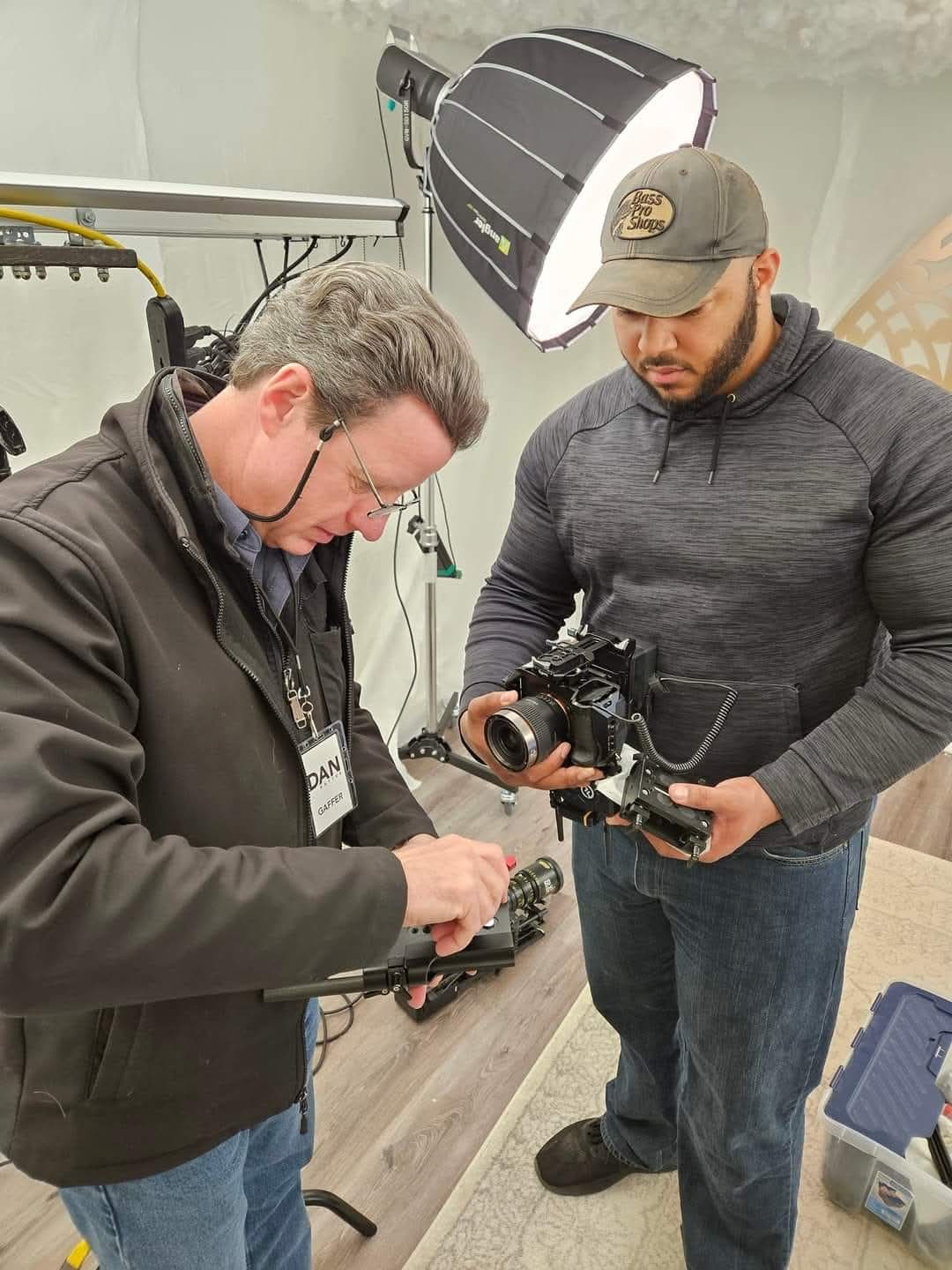 Preparing a cinema camera with a crew member beneath a studio softbox.